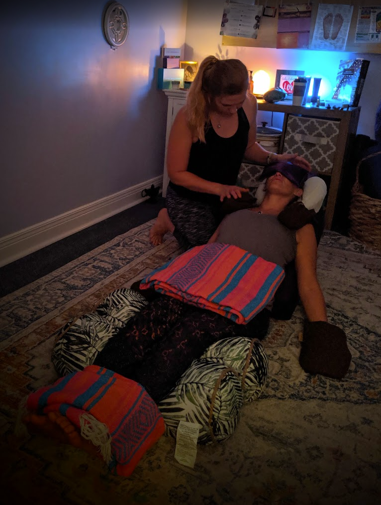 Laurel kneeling beside a reclining client during a floor session