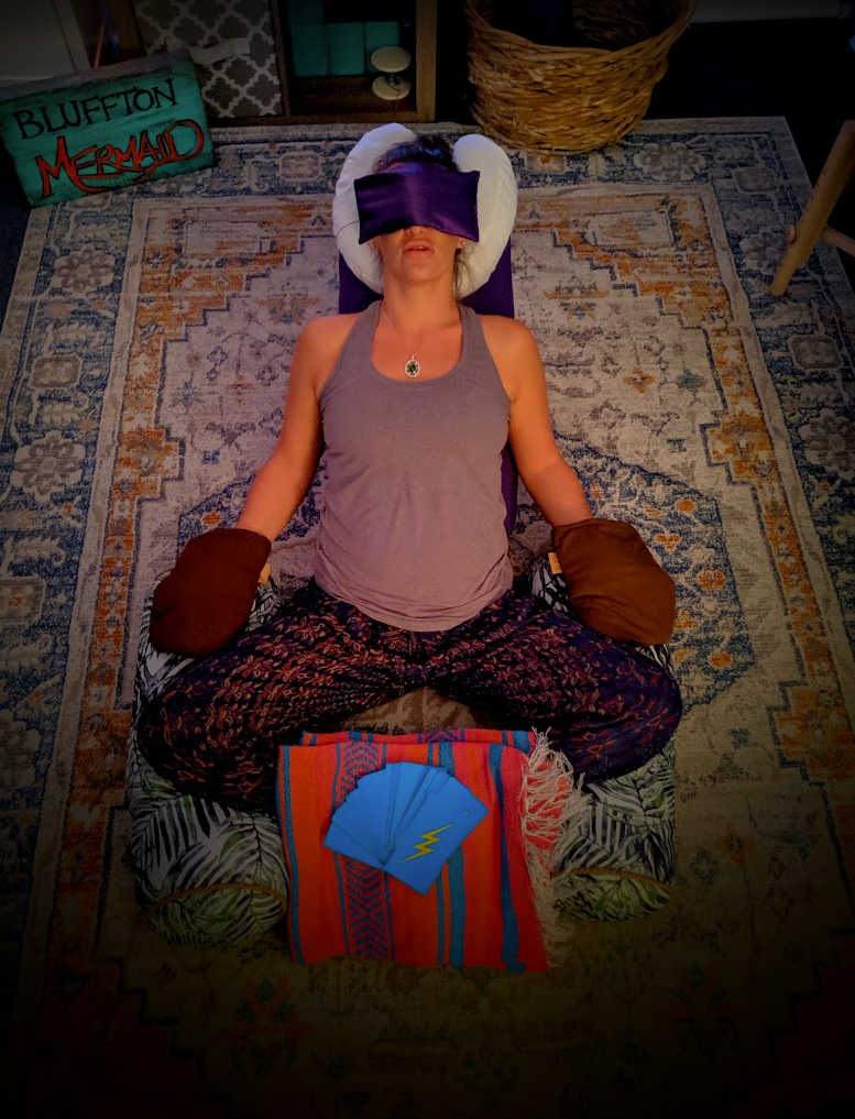 Client resting cross-legged with an eye pillow, wrapped in blankets