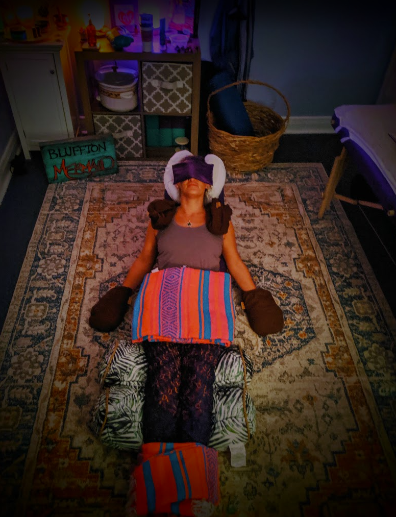 Client fully reclined on the studio rug wrapped in blankets and bolsters