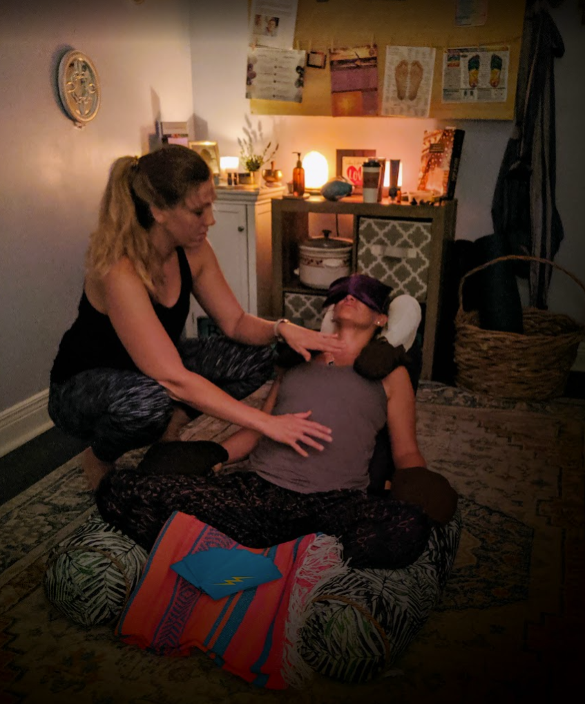 Laurel with hands over a reclining client's heart space