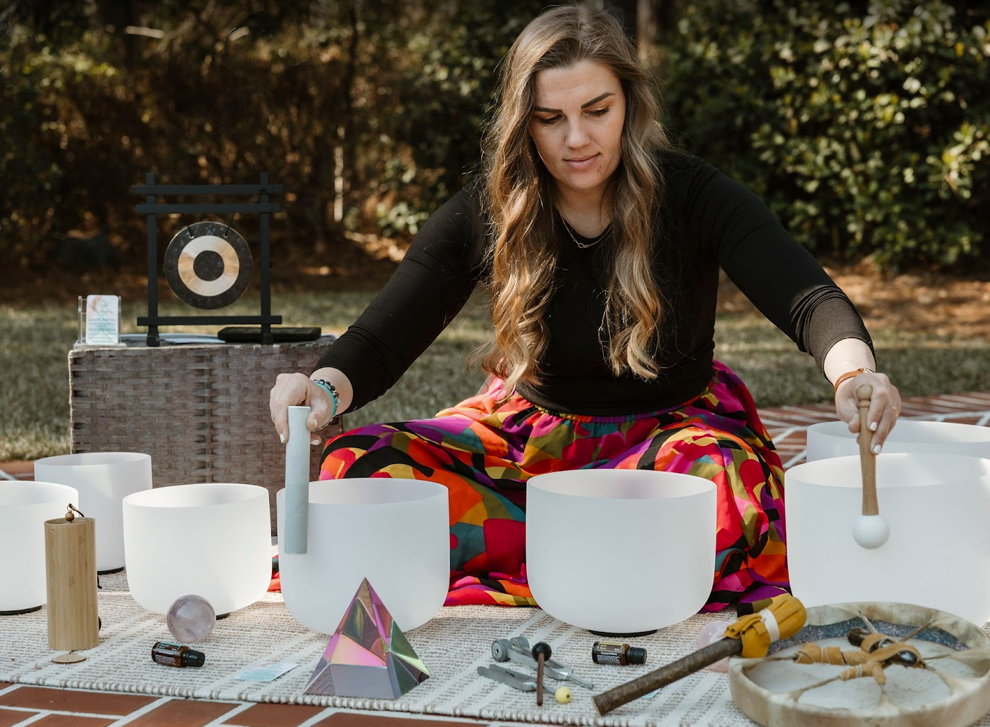 Laurel playing crystal singing bowls at an outdoor sound healing session